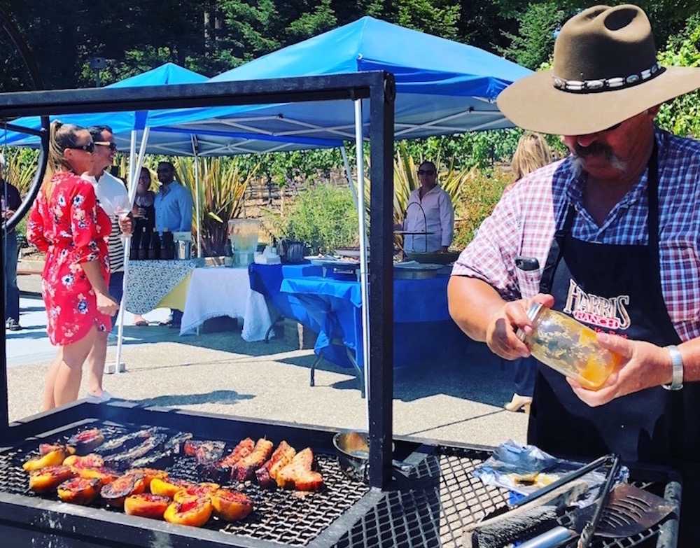A man in a hat is preparing food on a grill.