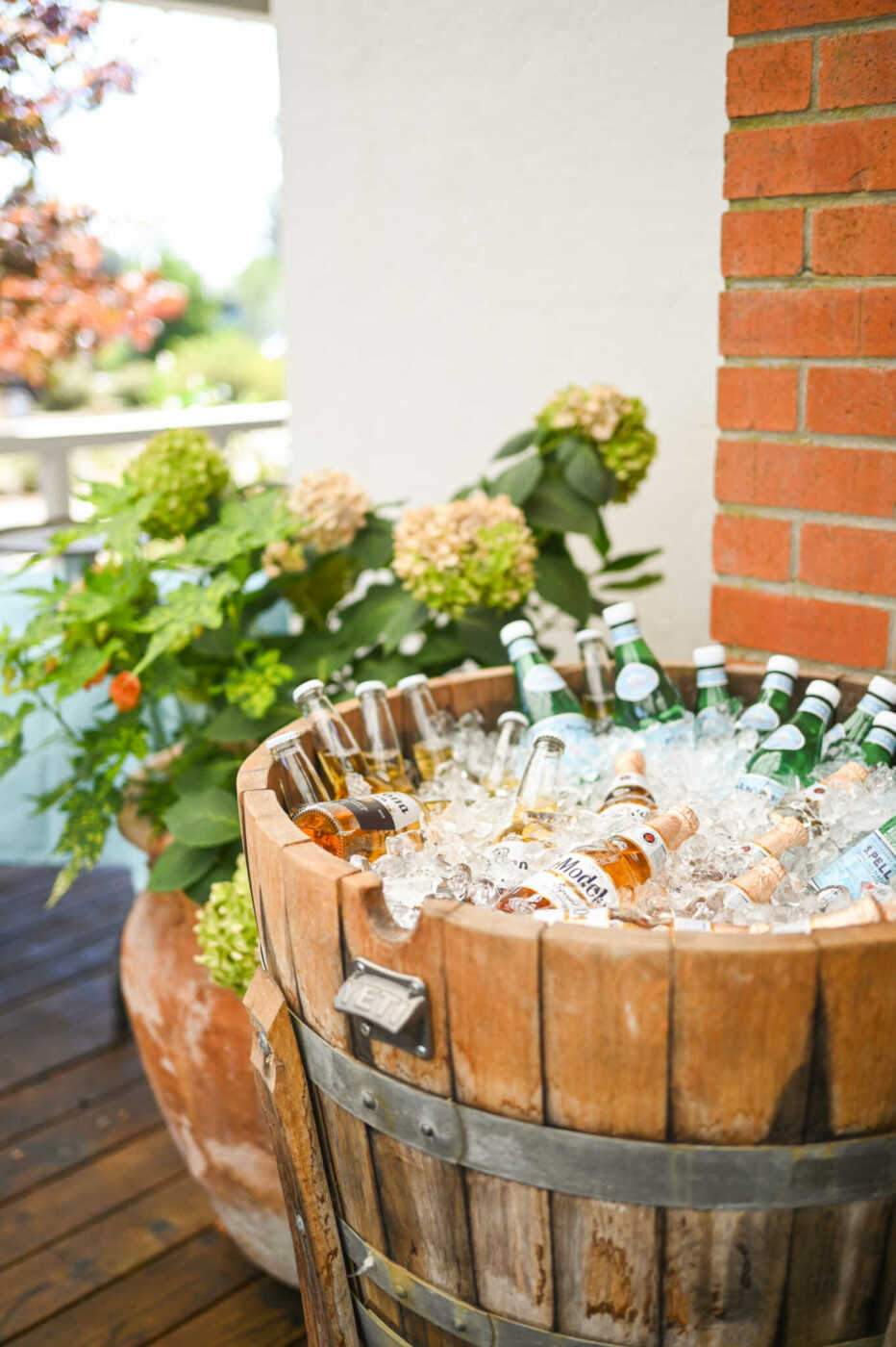 A wooden barrel filled with beer bottles on a wooden deck.