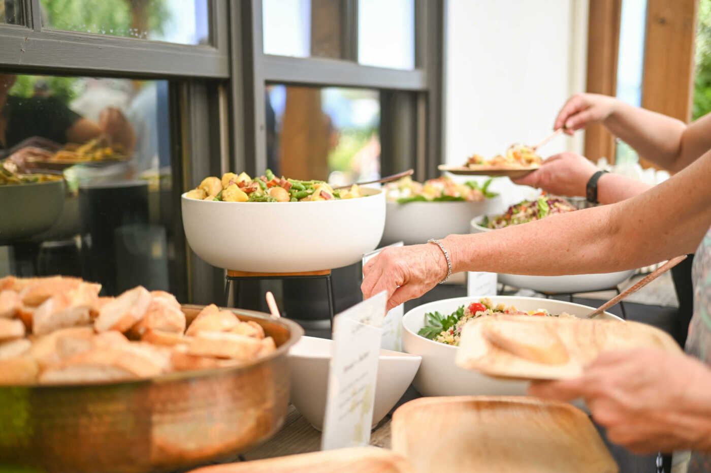 A group of people serving food at a buffet.