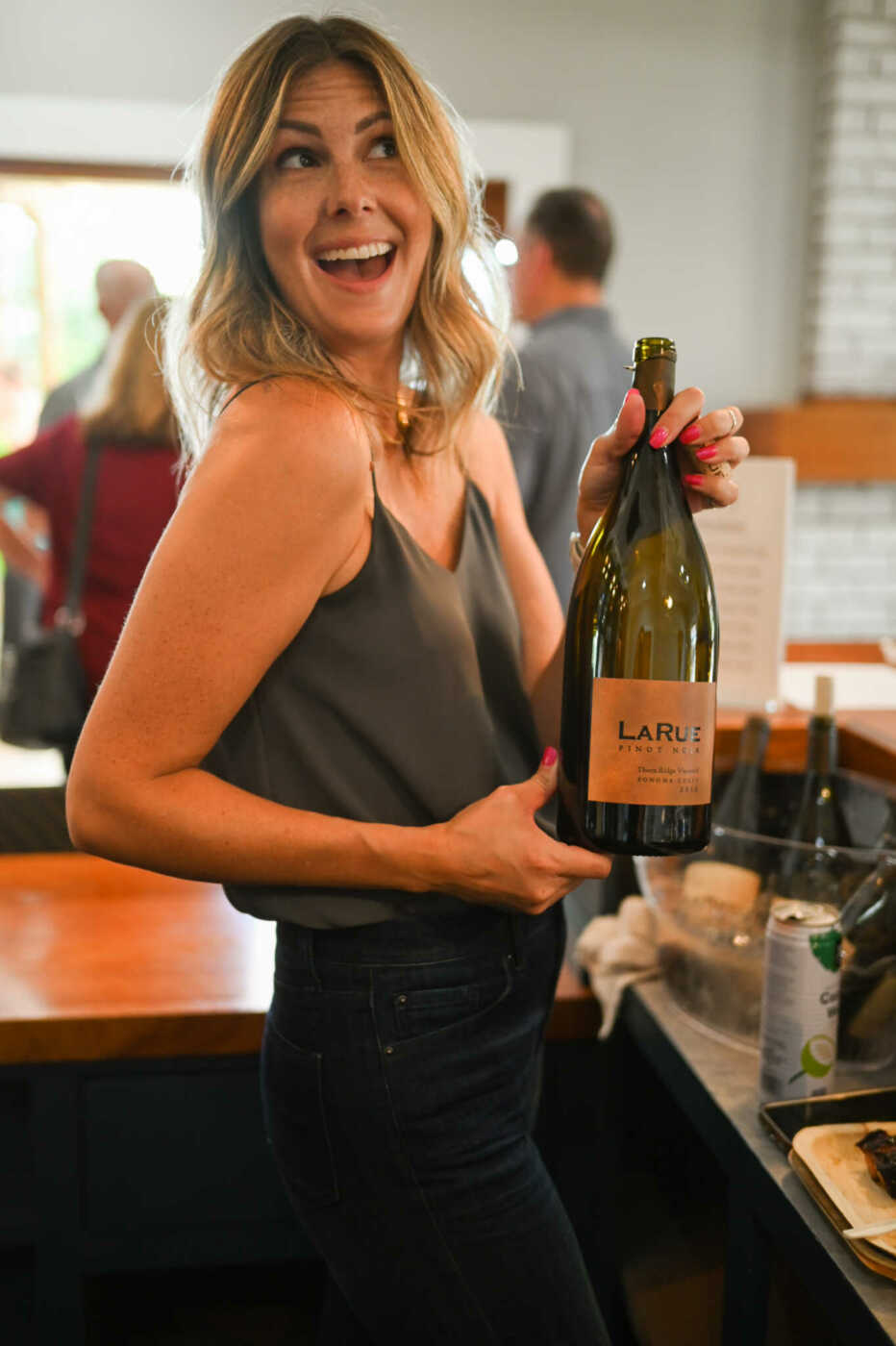 A woman holding a bottle of wine.